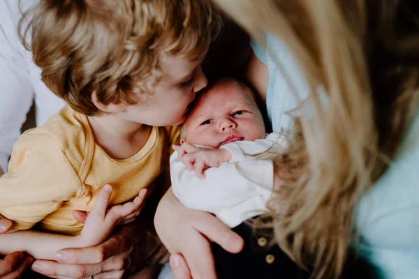 家で生まれたばかりの赤ん坊の弟にキスをする小さな男の子. — ストック写真