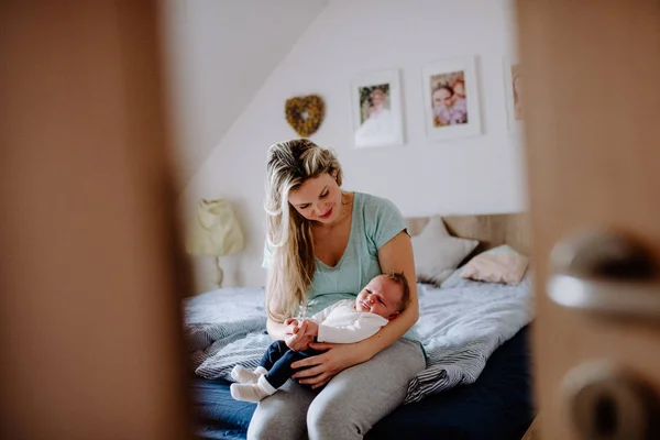 Uma bela jovem mãe com um bebê recém-nascido em casa . — Fotografia de Stock