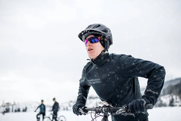 Zijaanzicht van mountainbikers rijden in sneeuw buitenshuis in winter natuur. — Stockfoto