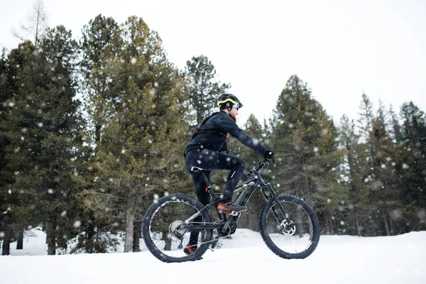 Side view of mountain biker riding in snow outdoors in winter nature. — Stock Photo, Image