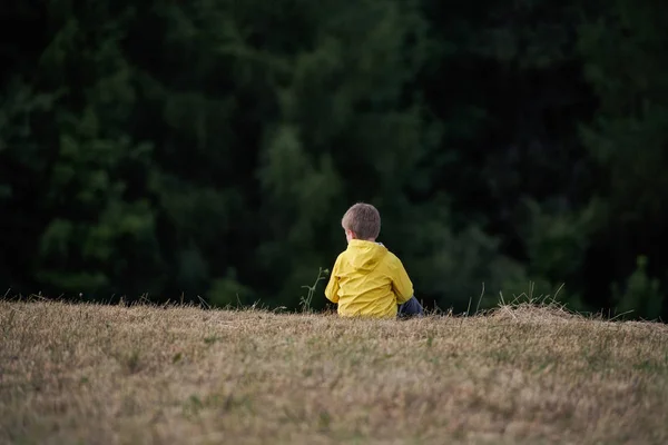 Vista posteriore del bambino della scuola seduto in gita nella natura, a riposo . — Foto Stock