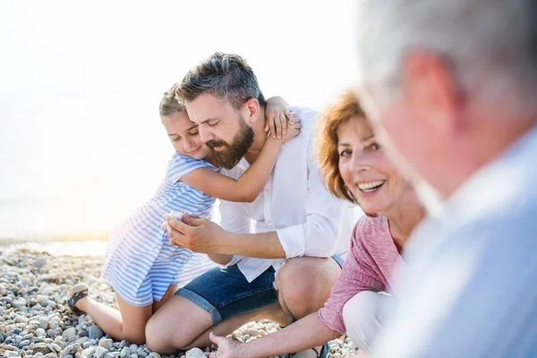 Familia multigeneracional en unas vacaciones sentada junto al lago, hablando . — Foto de Stock