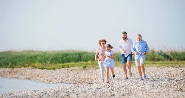 Familia multigeneracional en unas vacaciones en el paseo por el lago, corriendo . — Foto de Stock