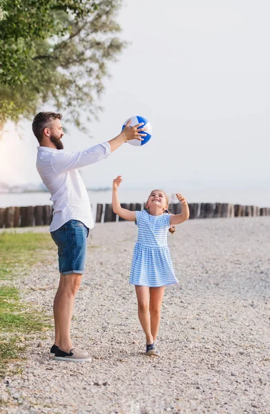 Vater und kleine Tochter spielen im Urlaub am See. — Stockfoto