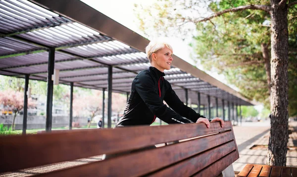 Un retrato de una joven deportista haciendo ejercicio al aire libre en el parque, estirándose . —  Fotos de Stock