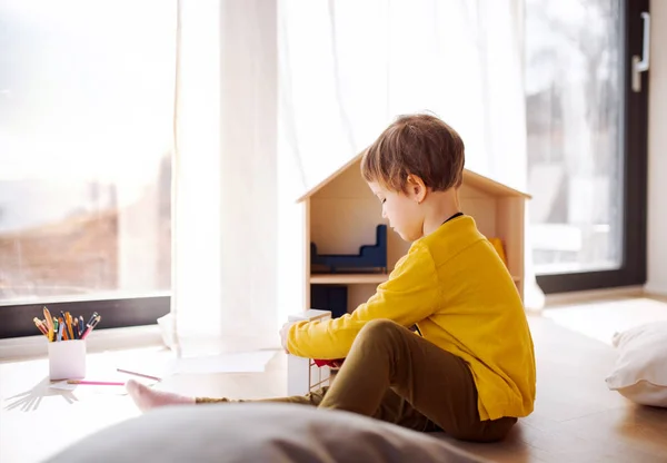 Una bambina che gioca con la casa di legno sul pavimento a casa . — Foto Stock