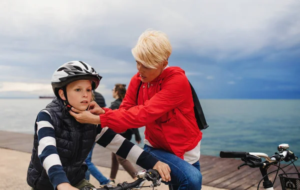 ビーチに立って屋外で自転車を持つ母と小さな息子. — ストック写真