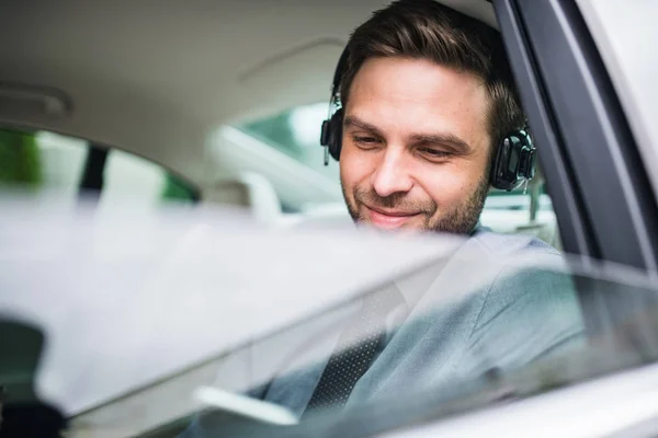 헤드폰, 셔츠와 넥타이 차에 앉아 젊은 행복 비즈니스 남자. — 스톡 사진