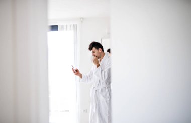 Yatak odasında kahve ve akıllı telefon ile genç adam, bir sabah rutin.