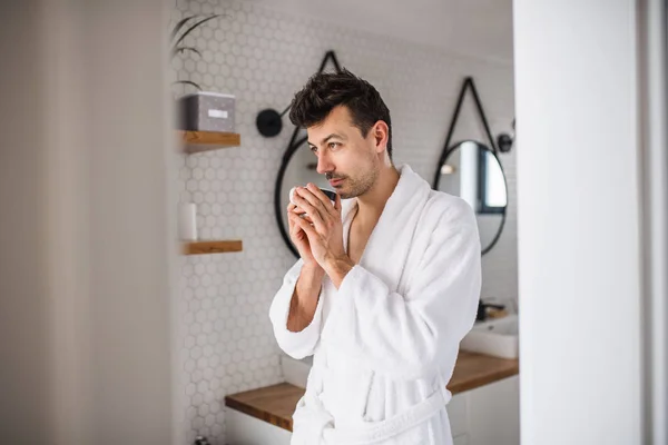 Young man with coffee in the bathroom in the morning. — Stock Photo, Image