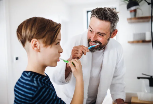 Reifer Vater mit kleinem Sohn morgens im Badezimmer beim Zähneputzen. — Stockfoto