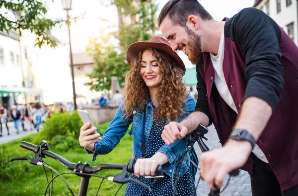 Jovem casal com scooters elétricos e smartphone na cidade, tirando selfie . — Fotografia de Stock