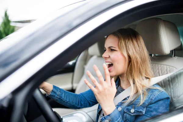 Angry young woman driver sitting in car, shouting. — Stock Photo, Image