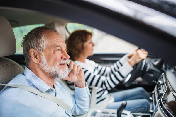 Glückliches Senioren-Paar mit Smartphone sitzt im Auto und redet. — Stockfoto
