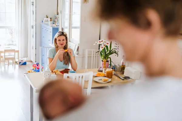 Părinți tineri frumoși, cu un nou-născut acasă, mâncând micul dejun . — Fotografie, imagine de stoc