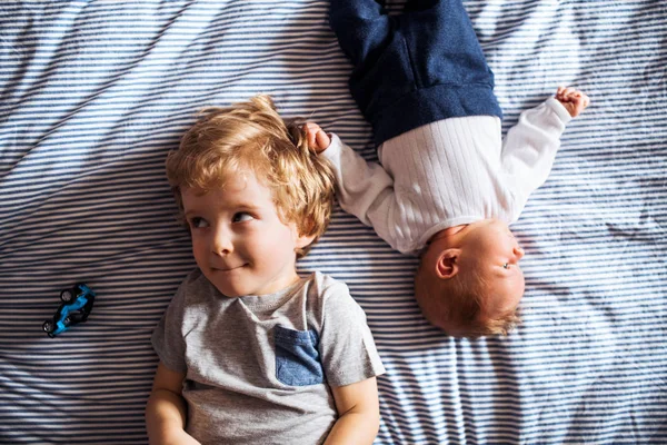 Una vista superior de un niño pequeño con un hermano recién nacido en casa . —  Fotos de Stock