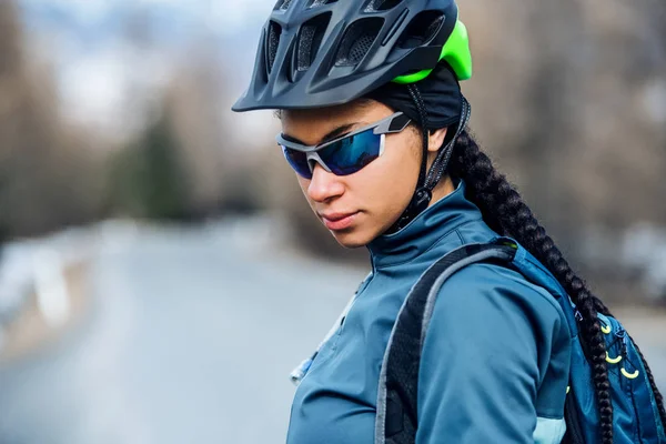 Vrouwelijke mountainbiker staande op de weg in de winter. — Stockfoto