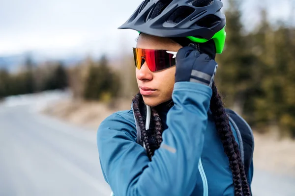 Vrouwelijke mountainbiker staande op de weg in de winter. — Stockfoto