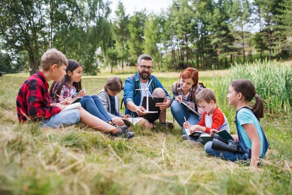 Grupo de escolares con maestro y modelo de molino de viento en excursión en la naturaleza . — Foto de Stock