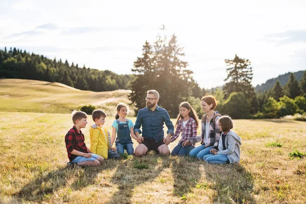 Group of school children with teacher on field trip in nature, holding hands. — Stock Photo, Image