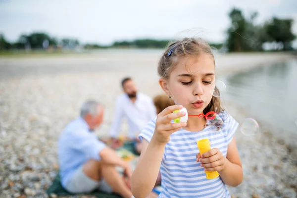 Frontansicht eines kleinen Mädchens im Urlaub am See, das Seifenblasen macht. — Stockfoto