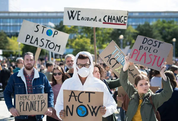 Люди с плакатами и защитным костюмом на глобальной забастовке за изменение климата . — стоковое фото