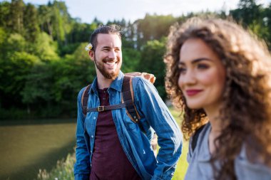 Doğada göl kenarında yürüyüş genç turist çift gezginler.