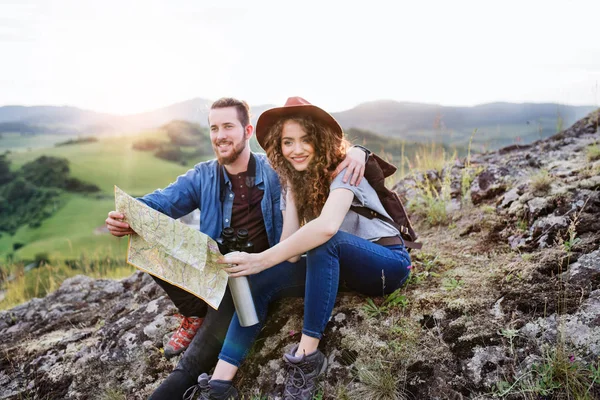 Joven pareja de turistas viajeros con mochilas senderismo en la naturaleza, utilizando el mapa . — Foto de Stock
