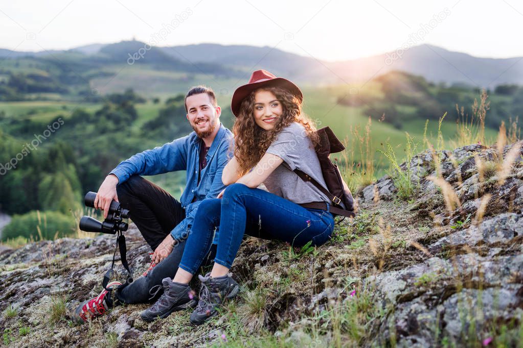 Young tourist couple travellers with binoculars hiking in nature, resting.