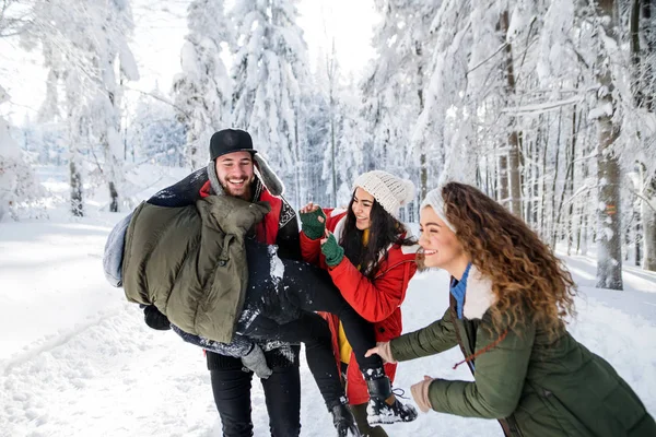 Un grupo de jóvenes amigos divirtiéndose al aire libre en la nieve en el bosque de invierno . — Foto de Stock
