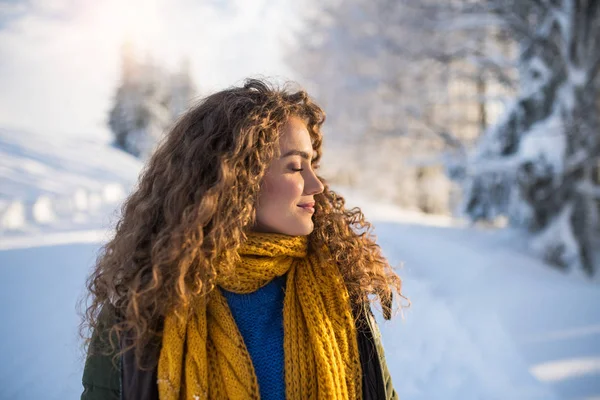 雪の冬の森の中で屋外に立っている若い女性の正面図. — ストック写真