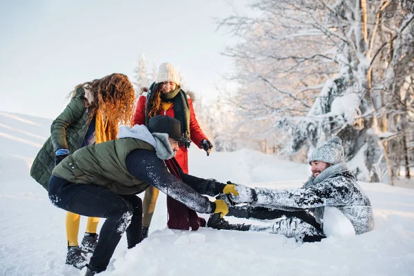 En grupp unga vänner på en promenad utomhus i snö i vinterskogen. — Stockfoto