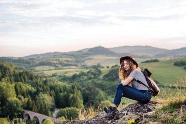 Doğada oturan sırt çantası ile genç turist kadın gezgin.