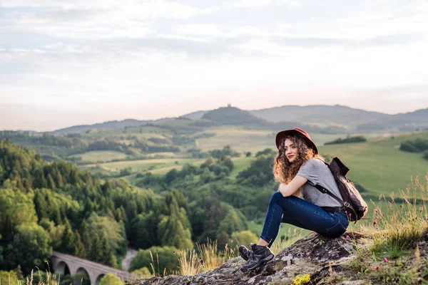 自然の中に座ってバックパックを持つ若い観光女性旅行者. — ストック写真