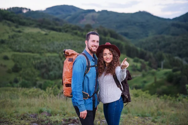 Jong toeristisch paar reizigers met rugzakken wandelen in de natuur, praten. — Stockfoto