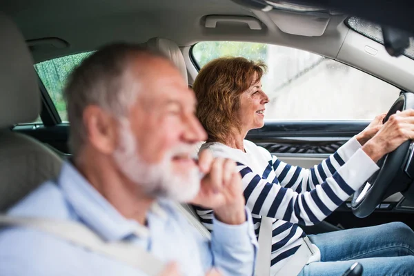 Glückliches Senioren-Paar mit Smartphone im Auto sitzend, unterwegs. — Stockfoto