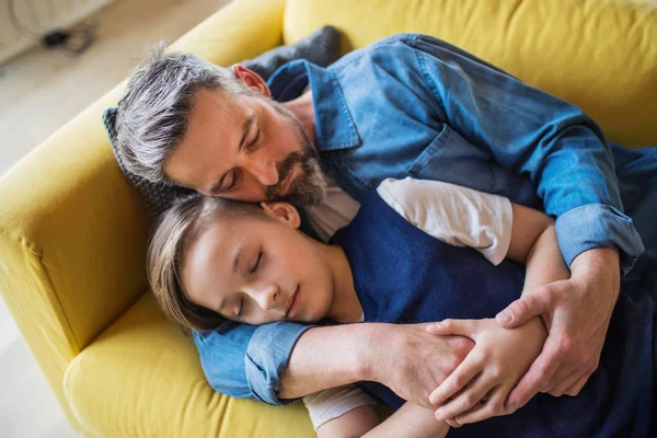 Зрілий батько з маленьким сином лежить на дивані в приміщенні, спить і відпочиває . — стокове фото