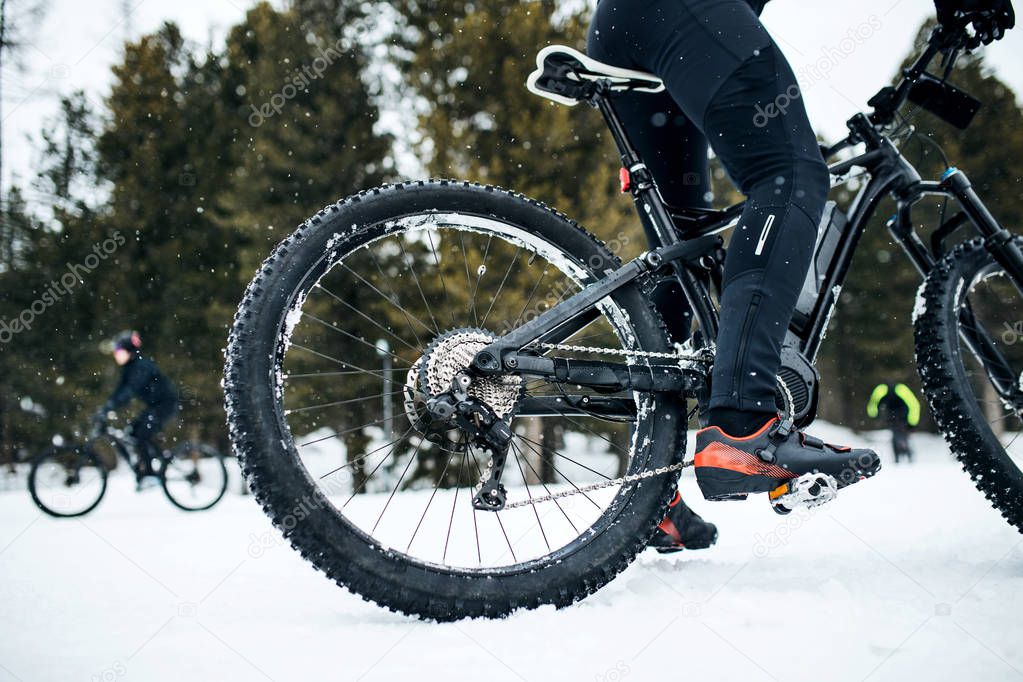 Midsection of mountain biker riding in snow outdoors in winter.