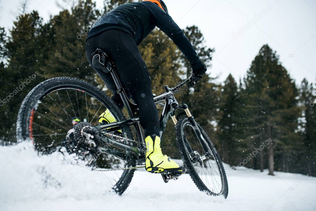 Midsection of mountain biker riding in snow outdoors in winter.