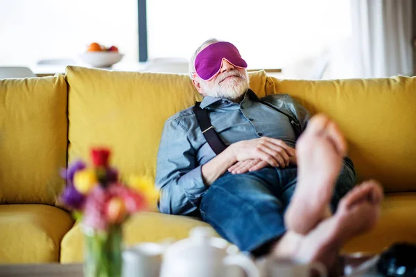 Homme âgé avec masque pour les yeux couché sur le canapé à l'intérieur à la maison, relaxant . — Photo