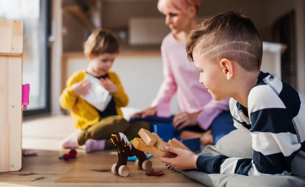 Una joven con dos hijos jugando en el suelo . — Foto de Stock