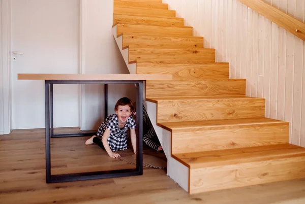 Děti si hrají doma, schovávají se pod schody. — Stock fotografie