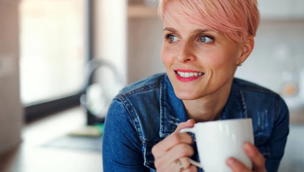 Eine junge attraktive Frau, die sich zu Hause in einer Küche auf eine Theke stützt. — Stockfoto