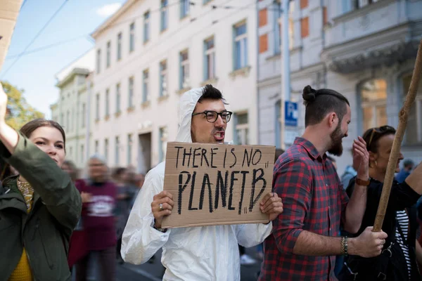 在全球气候变化罢工中，人们举着标语牌和防护服. — 图库照片