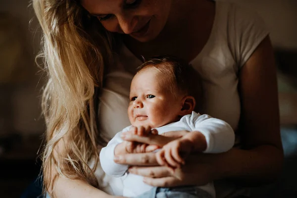 Een mooie jonge moeder met een pasgeboren baby thuis. — Stockfoto