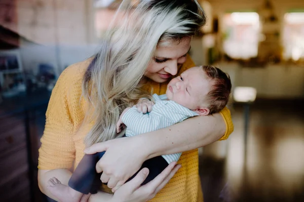 A beautiful young mother with a newborn baby at home. Shot through glass. — Stock Photo, Image