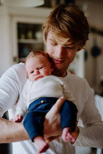 Uma visão frontal do jovem pai segurando um bebê recém-nascido em casa . — Fotografia de Stock