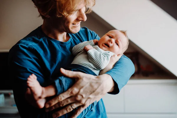 Вид спереди на молодого отца, держащего новорожденного ребенка дома . — стоковое фото