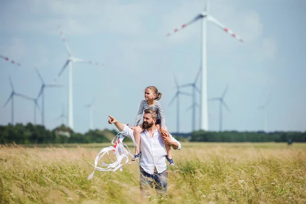 成熟的父亲与小女儿走在风电场的田野上. — 图库照片