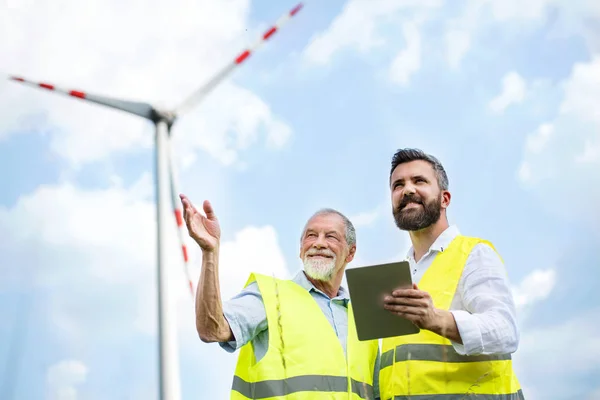 Engineers standing on wind farm, making notes. — Stock Photo, Image